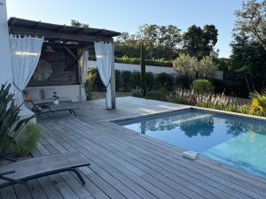 een houten terras met een zwembad en een pergola bij suara in Pinarellu