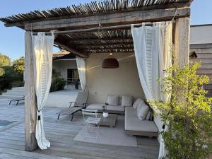 een pergola met een bank en een tafel op een patio bij suara in Pinarellu