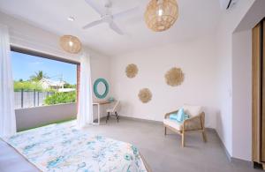 a bedroom with a bed and a chair and a window at Residence ORYAM in Trou aux Biches