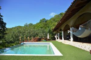 a swimming pool with a hammock next to a house at Casa Andalucia in San Juan del Sur