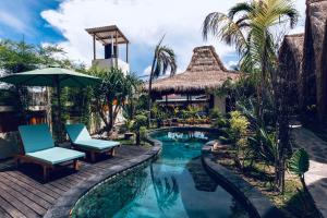 ein Pool in einem Resort mit zwei Liegestühlen und einem Sonnenschirm in der Unterkunft Corabelle Gili Air - Adults Only Boutique Retreat in Gili Air