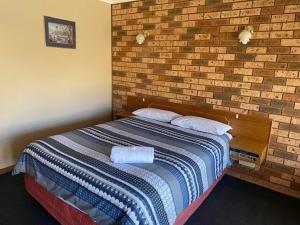a bed in a room with a brick wall at Lucky Strike Motel in Tomingley +14 photos