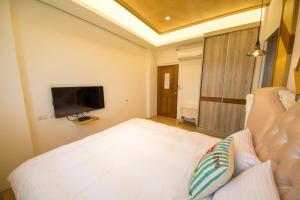 a bedroom with a white bed and a flat screen tv at Miller Homestay in Wujie +30 photos