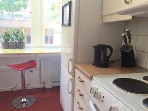 a kitchen with a stove and a red stool at Linné Hostel in Gothenburg