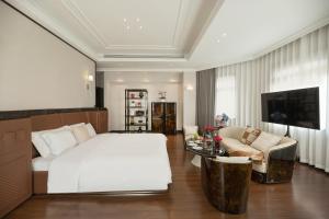 een slaapkamer met een bed, een bank en een televisie bij 青岛阿特拉酒店 in Qingdao