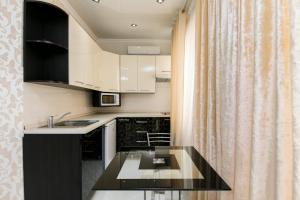 a kitchen with white cabinets and a black counter top at Apartment Lev Tolstoi in Chişinău