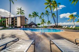 una piscina con palme e due sedie a sdraio di Papakea Resort Unit J303 a Lahaina