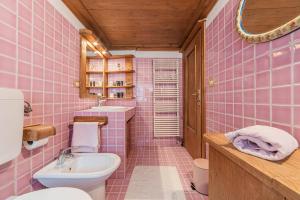 bagno piastrellato rosa con lavandino e servizi igienici di Da La Auri a Canale dʼAgordo