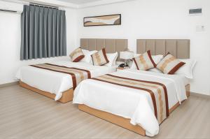 two beds in a hotel room with white at Vienna Hotel VN in Ho Chi Minh City