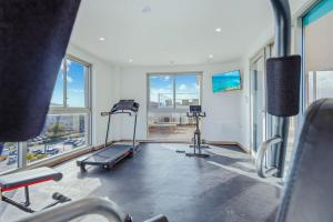une pièce avec une salle de sport avec un tapis roulant et des fenêtres dans l'établissement Modern 2BA2BR Condo Pool + Gym Near Palm Beach, à Palm-Eagle Beach