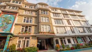 un grand bâtiment avec des fleurs devant lui dans l'établissement 4Everstay Grand Luxury Sambhala Premium Rooms Free Parking & Wifi !!! Top Rated & Best Selling Hotel In Manali, à Manali