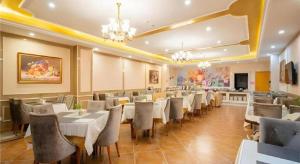 a restaurant with white tables and chairs in a room at Vienna Hotel Tianjin Zhongbei Town in Tianjin