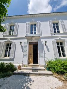 a white house with white shutters and a door at Manor house with pool in Le Tignet