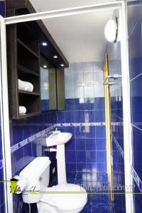 Baño de azulejos azules con aseo y lavamanos en Hotel Wampushkar, en Zamora