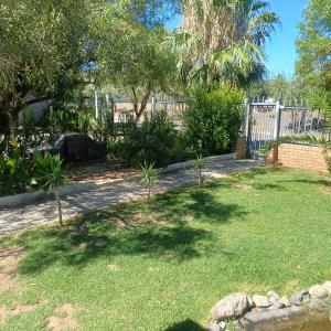 een tuin met een hek en wat bomen en gras bij Linga longa corner flat in Beaufort West