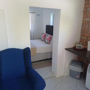 een woonkamer met een blauwe stoel en een bed bij Linga longa corner flat in Beaufort West