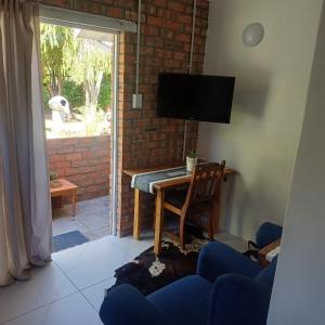 een woonkamer met een tv en een tafel met een stoel bij Linga longa corner flat in Beaufort West