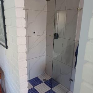 een douche met een glazen deur in een badkamer bij Linga longa corner flat in Beaufort West +7 foto's