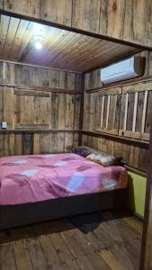 una camera da letto con un letto in una parete di legno di Castelo dos Caramujos a Anastácio