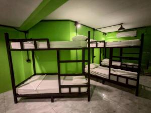 three bunk beds in a room with green walls at Dee-maak Hostel in Thongsala +7 photos