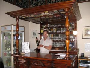 a man standing behind a bar with a bottle of wine at Ugbrooke Country Estate in Lower Dashwood