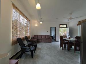 a living room with a couch and a table and chairs at Lagoonai Villa in Sinimodera