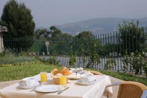 a table with a plate of food and two cups of orange juice at Hotel do Lago in Braga