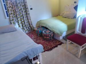 una camera con due letti, una sedia e un tappeto di Roma House a Aswan