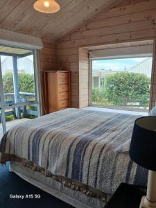 een slaapkamer met een groot bed en een groot raam bij A Waihi Beach Getaway in Waihi Beach