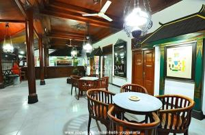 een eetkamer met tafels en stoelen en een plafond bij Hotel Batik Yogyakarta in Yogyakarta