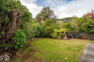 een achtertuin met een tafel, stoelen en bomen bij Sea View Batch in Takaka