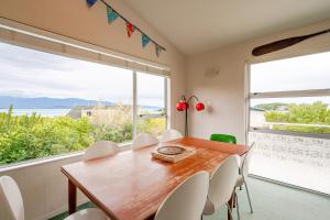 een eetkamer met een tafel en stoelen en een groot raam bij Sea View Batch in Takaka +51 foto's