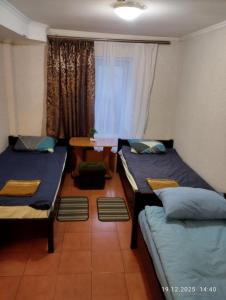 ein Zimmer mit zwei Betten, einem Tisch und einem Fenster in der Unterkunft Optimal 1 in Kiew