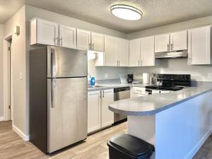 a kitchen with white cabinets and a stainless steel refrigerator at Cozy One-Bedroom Haven with Big Balcony in Vancouver