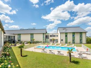 een uitzicht op een resort met een zwembad en een gazon bij Hôtel Ibis Styles Bourges in Bourges