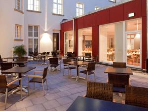 een restaurant met tafels, stoelen en ramen bij ibis Karlsruhe Hauptbahnhof in Karlsruhe