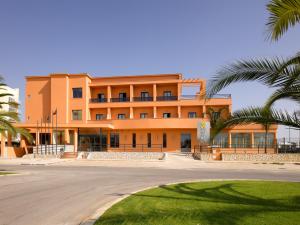 een groot oranje gebouw met palmbomen ervoor bij Hotel Praia Sol in Quarteira