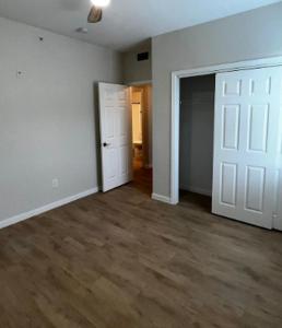 un soggiorno vuoto con pareti bianche e pavimenti in legno di Riata Apartments a Dallas