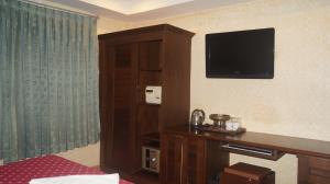 a hotel room with a television on the wall at Queen Victoria Inn in Pattaya
