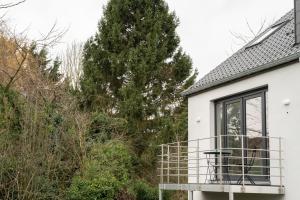 a white house with a balcony and a tree at Apartment - 3 guests in Mont-Saint-Guibert