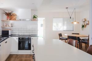 een keuken met witte kasten en een tafel met stoelen bij Whitsunday Wanderluxe in Cannonvale