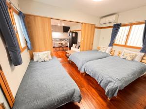 two beds in a room with wooden floors at HAMARs ITOMAN HOUSE - ReFaｼｬﾜｰﾍｯﾄﾞ&ﾄﾞﾗｲﾔｰ完備 - 南部観光の拠点 - 1日1組限定 in Itoman +46 photos