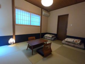 een kamer met een tafel, stoelen en een raam bij Guesthouse Nobi in Kyoto
