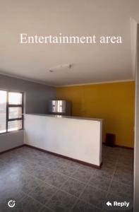 an empty room with a white counter and a yellow wall at Pluto Guesthouse in Walvis Bay +1 photo