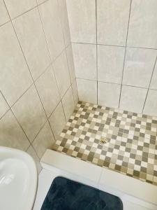 a bathroom with a toilet and a checkered floor at Pluto Guesthouse in Walvis Bay