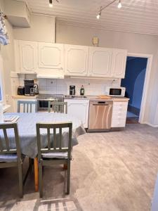 een keuken met witte kasten en een tafel en stoelen bij Stilla Hem in Tranemo +6 foto's