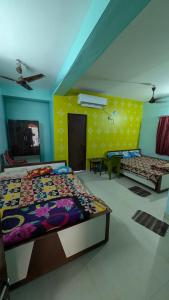a bedroom with two beds and a yellow wall at Ashirbad hotel in Digha