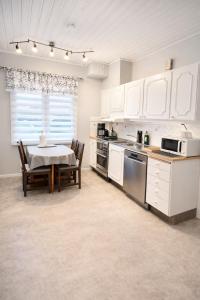 een keuken met witte kasten en een tafel met een eetkamer bij Stilla Hem in Tranemo