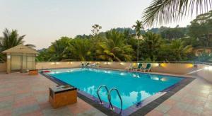 a swimming pool in a resort with trees and palm trees at Devon Hotel in Kandy