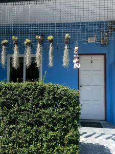 een blauw gebouw met een witte deur en wat planten bij Yada House s&s in Nai Yang Beach